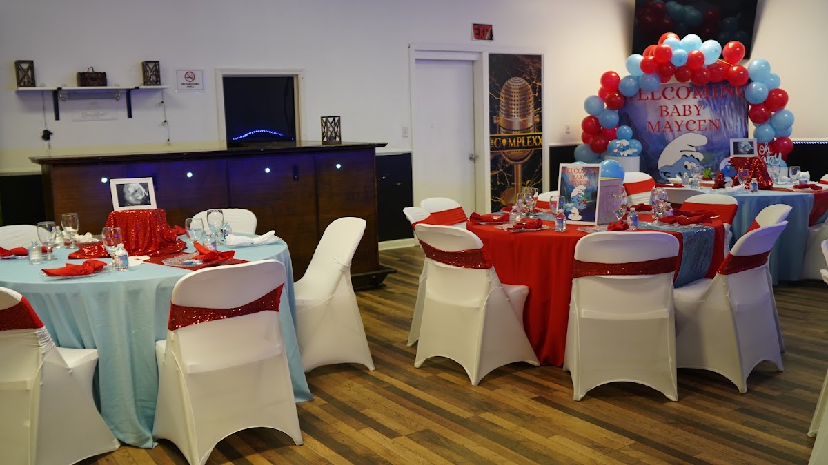 An event laid out at The Complexx ATL with draped round tables, chair sashes, and a balloon arch