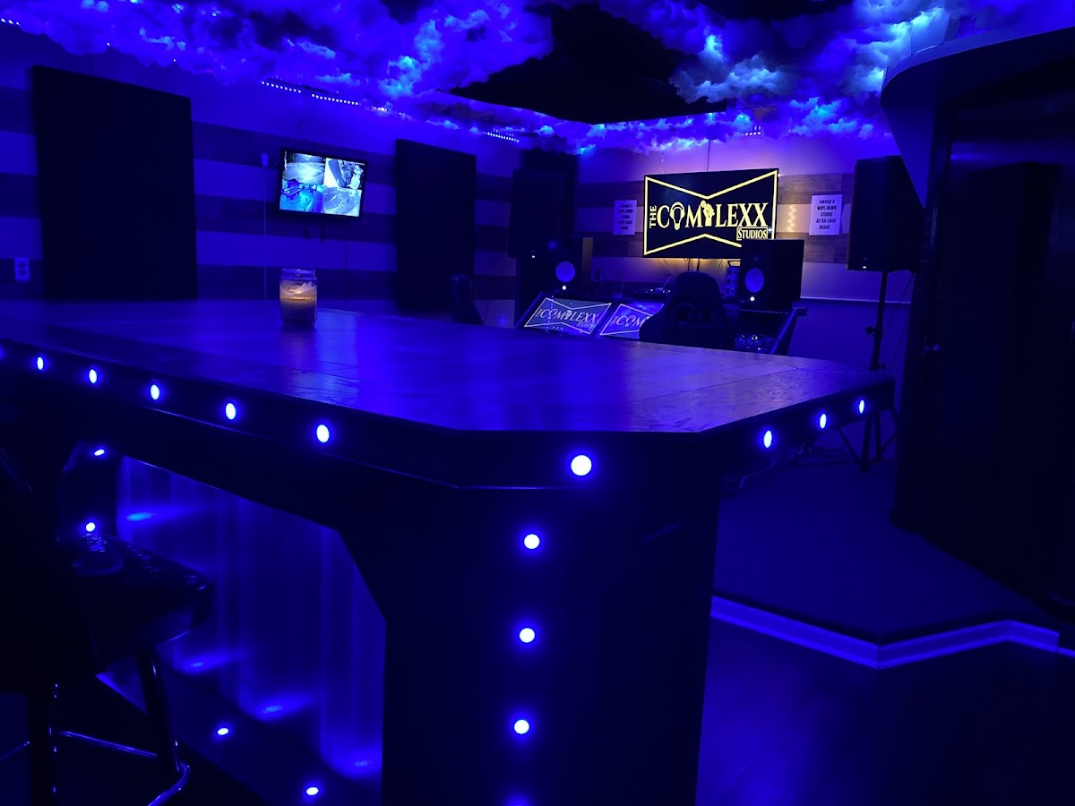 The Complexx ATL lounge bathed in electric blue light with the studio's neon sign in Stockbridge, GA